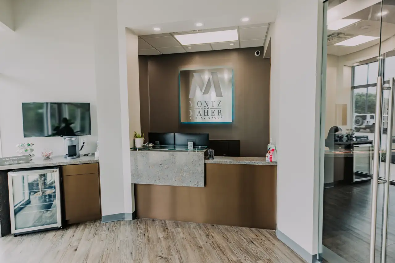 The front desk and refreshment bar at a Montz & Maher office, with the practice's M logo on the wall behind the desk.