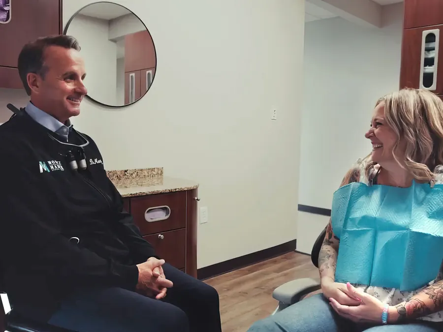 Dr. David Montz sitting and talking with a smiling patient in the treatment chair.